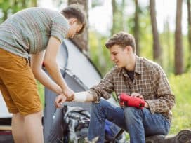 The man helps his injured friend to put a gauze on his wound.